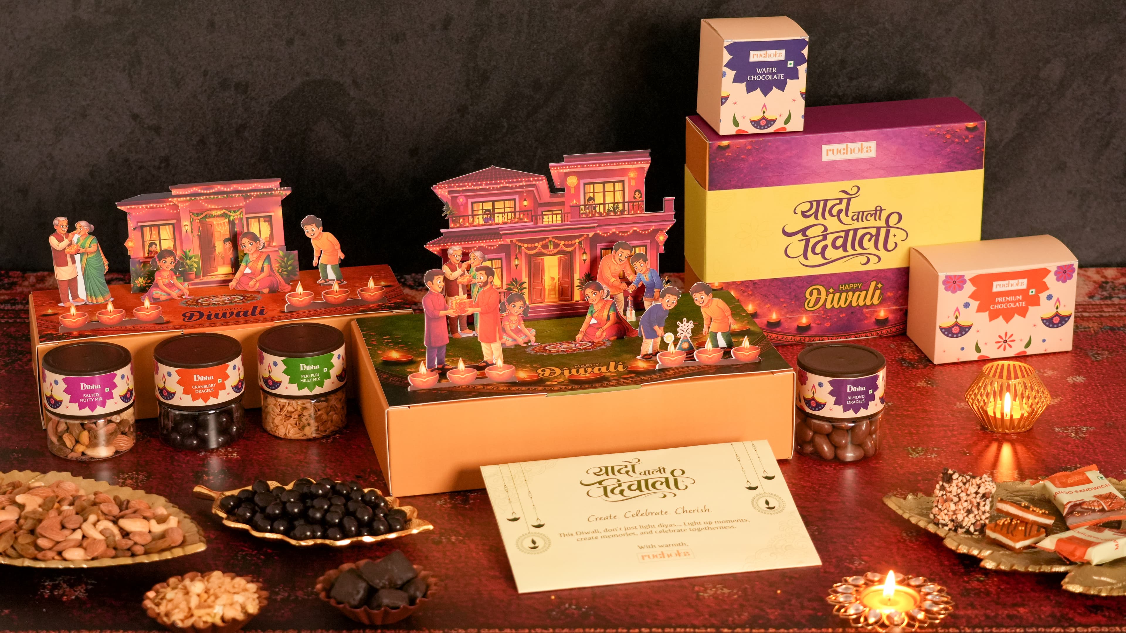 Ruchoks Diwali concept gift boxes with illuminated home scenes, chocolates, dry fruits and glowing diyas
